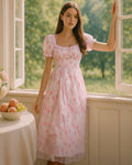 Dear Georgina pink floral midi dress with puff sleeves and cinched waist, featuring a vintage rose print on chiffon, styled at an open window with soft morning light, from the English Garden Party collection.